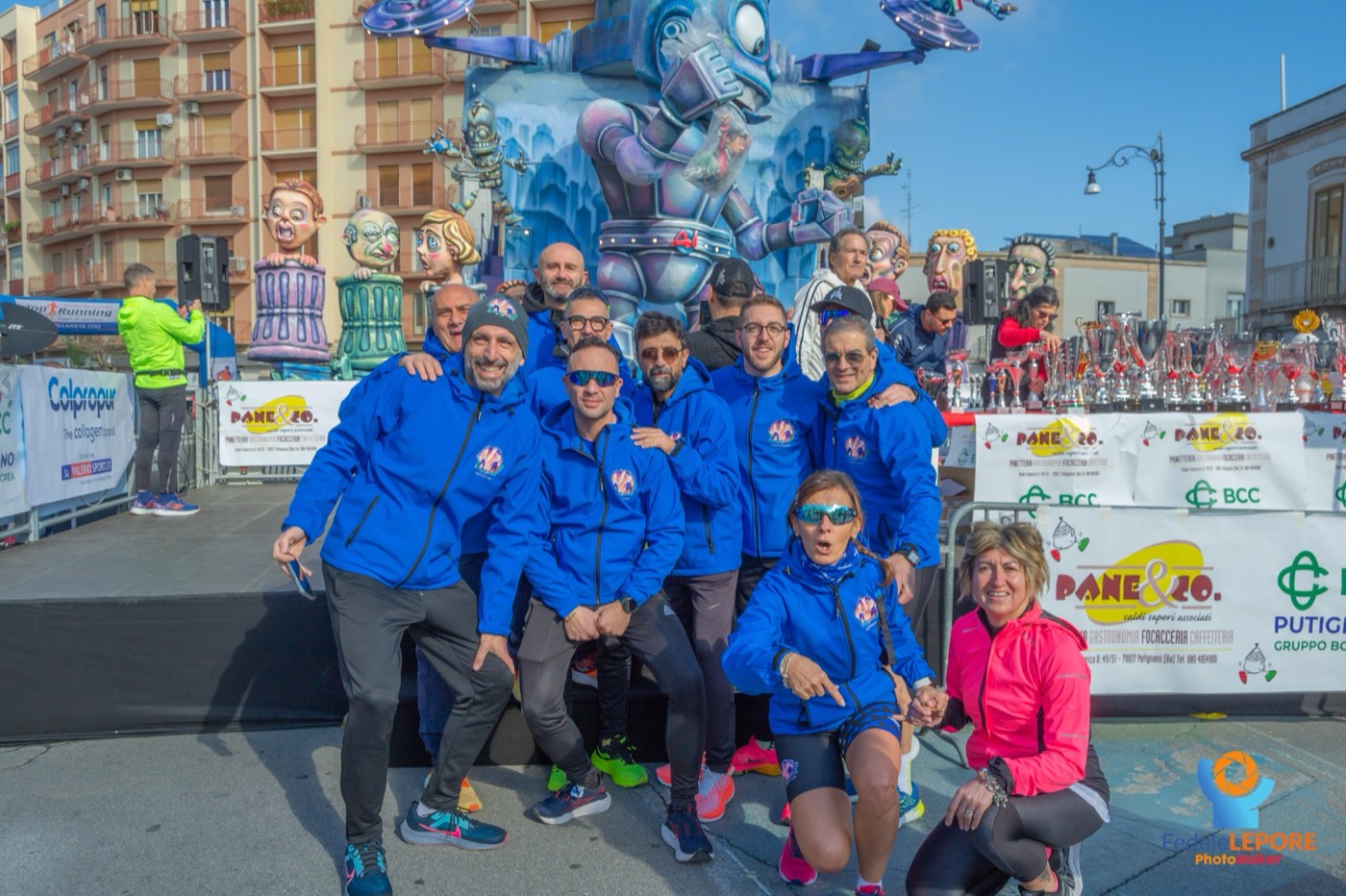 Il team con la giacca ufficiale in posa davanti a un carro allegorico